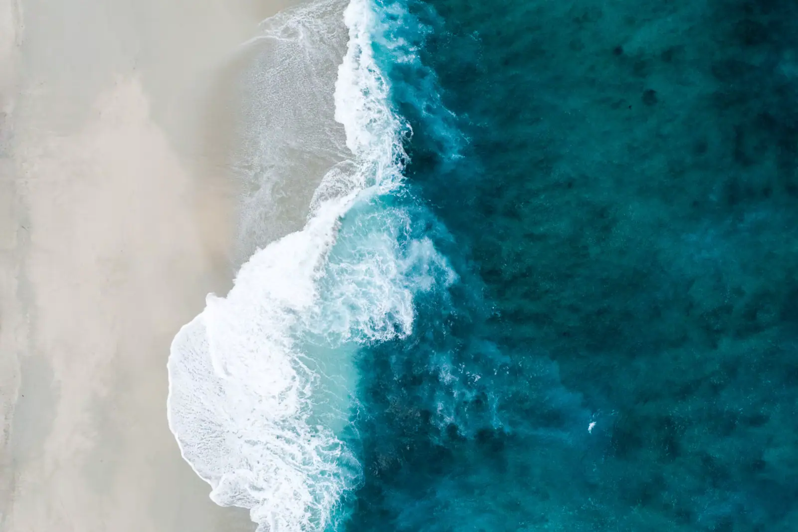 Heavy winter surf breaking across the mouth of a bay between two lava headlands